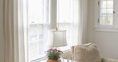 Уютный уголок в гостиной с белыми шторами, креслом и столиком у окна.