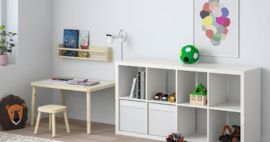 Белый модульный стеллаж для игрушек в светлой детской со столом, ковром и деревянным поездом